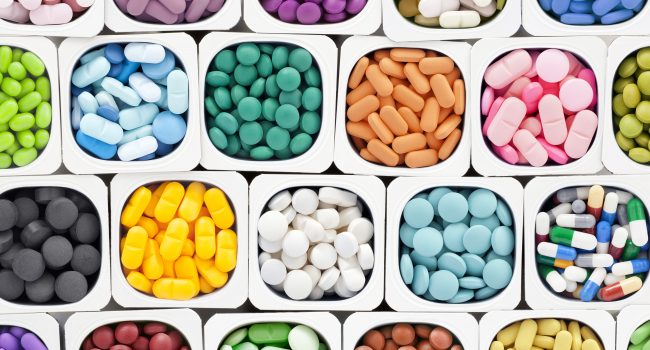 Varieties of multicolored pills inside plastic container
